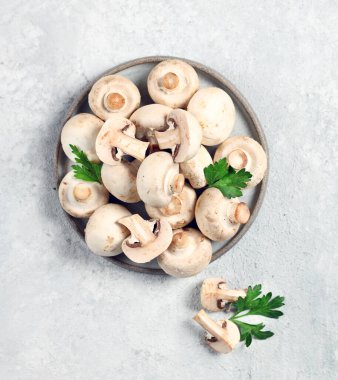 Açık gri arka plan manzaralı gri tabakta taze şampiyon mantarları.