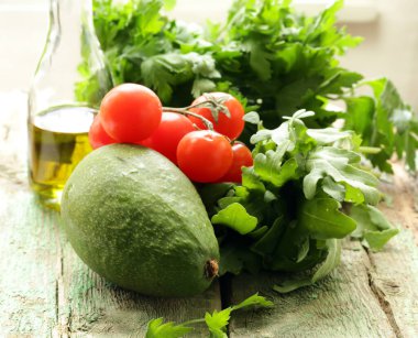 Tahta arka planda taze avokado ve yeşiller.