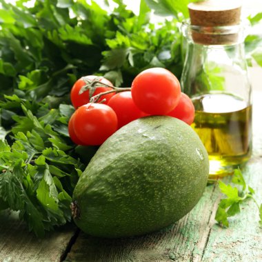 Tahta arka planda taze avokado ve yeşiller.