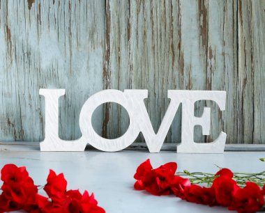 Aşk kelimesi ahşap arka planda çiçeklerle, sevgililer gününde