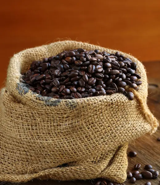 coffee beans in a canvas bag on a wooden background