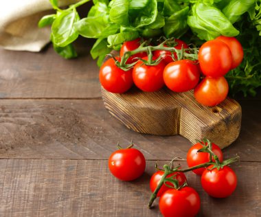 Taze organik domates ve ahşap arka planda fesleğen.