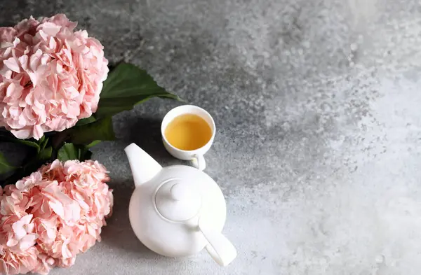teapot tea and flowers on a gray background