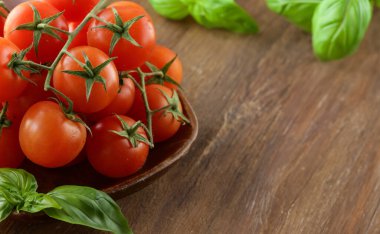 Kiraz domates ve fesleğen ahşap arka plan üzerinde