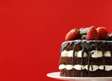 Kırmızı arka planda böğürtlenli çikolatalı pasta.