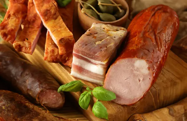 assorted smoked meat delicacies on a wooden board