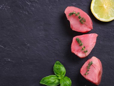 Siyah arkaplanda taze çiğ ton balığı filetosu.