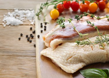 Tahtada aromatik bitkilerle çiğ ördek filetosu.