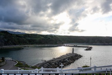 Bulutlu gökyüzünün altında, İspanya, Luarca balıkçı limanının çıkışından manzarayı izle