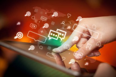 İçinden sohbet simgeleri çıkan tablet kullanan bir elin yakın plan resmi, sosyal medya kavramı
