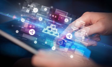 Altın külçeli tablet kullanan bir elin yakın plan fotoğrafı, dijital para birimi konsepti