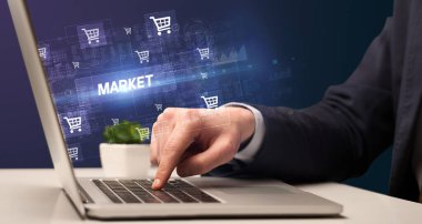 MARKET yazıtları ve online alışveriş konseptiyle dizüstü bilgisayarda çalışan bir işadamı