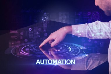 İş adamı, AUTOMATION yazıtları ve modern teknoloji konseptiyle büyük ekrana dokunuyor.