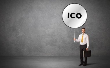 Genç iş adamı ICO kısaltmalı trafik levhası taşıyor, teknoloji çözüm kavramı