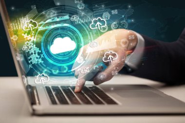 Multimedya ekranından çıkan bulut simgesiyle modern bir dizüstü bilgisayarda yazı yazan iş adamı, sezgisel teknoloji kavramı