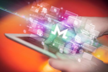 İçinden monero simgeleri çıkan tablet kullanan bir elin yakın çekimi, dijital para birimi kavramı