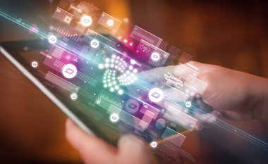 Tablet kullanan bir elin yakın plan resmi, tabletten çıkan iota simgeleri, dijital para birimi konsepti