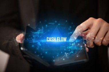 İş adamı elinde CASH FLOW yazıtlı, iş konsepti olan katlanabilir bir akıllı telefon tutuyor.