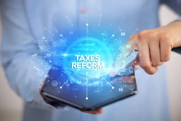 税金改革の碑文と折り畳み式のスマートフォンを保持するビジネスマン 新しいビジネスコンセプト — ストック写真