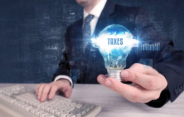 持有印有Taxes字样的灯泡的商人 新的商业概念 — 图库照片