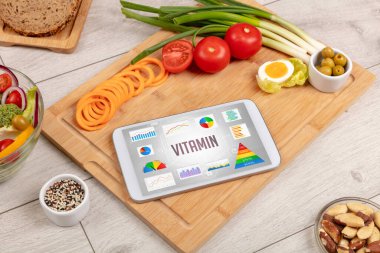 Organik gıda ve tablet bilgisayarı VITAMIN yazısını, sağlıklı beslenme bileşimini gösteriyor