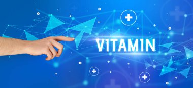 VITAMIN yazıtlarına işaret eden kırpılmış elin yakın çekimi, tıbbi konsept