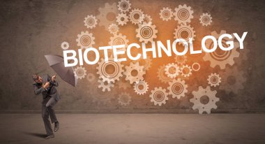 BIOTECHNOLOGY yazıtlarından şemsiyeyle savunma yapan iş adamı, teknoloji kavramı
