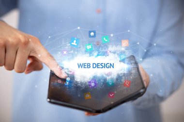 WeB DESIGN yazıtlı, teknoloji konseptli katlanabilir bir akıllı telefon tutan bir iş adamı