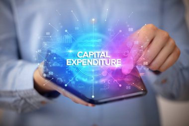 İş adamı elinde CAPITAL ExPENDITURE yazıtlı katlanabilir bir akıllı telefon tutuyor, yeni iş konsepti