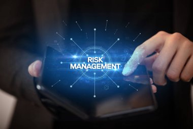 İş adamı, üzerinde Risk Yönetimi yazıtı ve yeni iş konsepti olan katlanabilir bir akıllı telefon tutuyor.