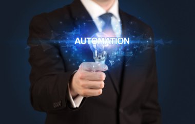 Otomasyon yazıtlı, yenilikçi teknoloji kavramlı bir iş adamı elinde ampul tutuyor.