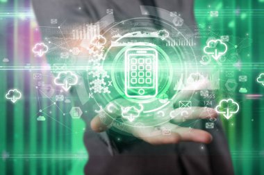 İş adamı elinde akıllı telefon simgesi ve etrafında birden fazla teknoloji sembolü tutuyor.