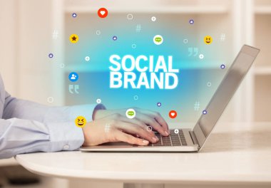 SOCIAL BRAND yazıtları ve sosyal medya kavramına sahip dizüstü bilgisayar kullanan serbest çalışan kadın