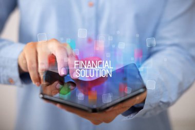 Elinde katlanabilir bir akıllı telefon tutan genç adam FINANCIAL SOLUTION yazıtları, eğitim konsepti