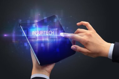 İş adamı katlanabilir bir akıllı telefon tutuyor INSURTECH yazıtları, yeni teknoloji konsepti