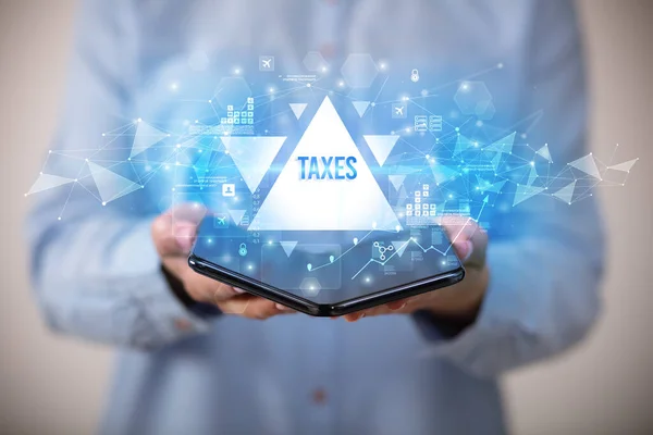 Επιχειρηματίας Κρατώντας Ένα Αναδιπλούμενο Smartphone Την Επιγραφή Taxes Επιχειρηματική Ιδέα — Φωτογραφία Αρχείου