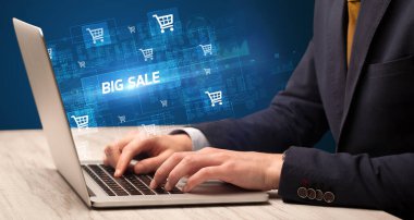 İş adamı, bilgisayarında BIG SALE yazıları ve online alışveriş konseptiyle çalışıyor.