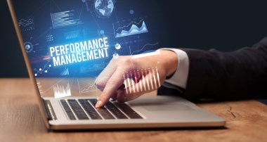 Dizüstü bilgisayarda Performans Yönetimi yazıtları ve yeni iş konseptiyle çalışan iş adamı.