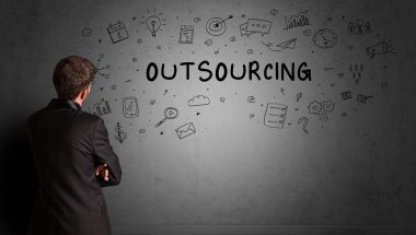 İş adamı, OutTSOURCING yazıtları ve iş stratejisi konseptiyle yaratıcı bir fikir çizimi yapıyor.