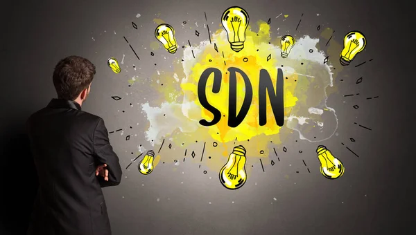 Sdnの略でカラフルな電球を描くビジネスマン 新しい技術のアイデアの概念 — ストック写真