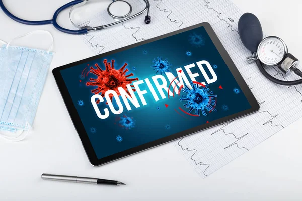 Tablet pc and doctor tools on white surface with CONFIRMED inscription, pandemic concept