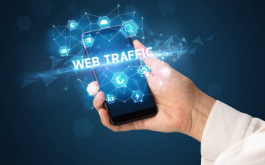 WebB TRAFFIC yazıtlı, modern teknoloji konseptli akıllı telefon tutan kadın.