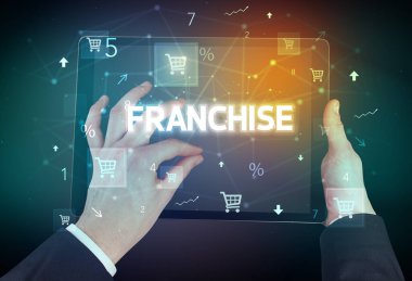 FRANCHISE yazıtları ve online alışveriş konseptiyle el ele tutuşma tabletinin yakın çekimi