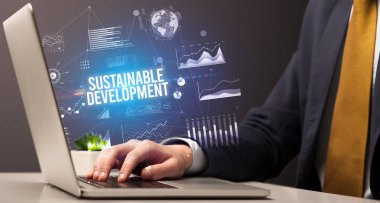 Sürdürülebilir Kalkınma yazıtları ve yeni iş kavramı ile dizüstü bilgisayarda çalışan işadamı