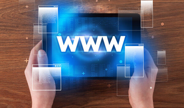 Close-up of a hand holding tablet with WWW abbreviation, modern technology concept