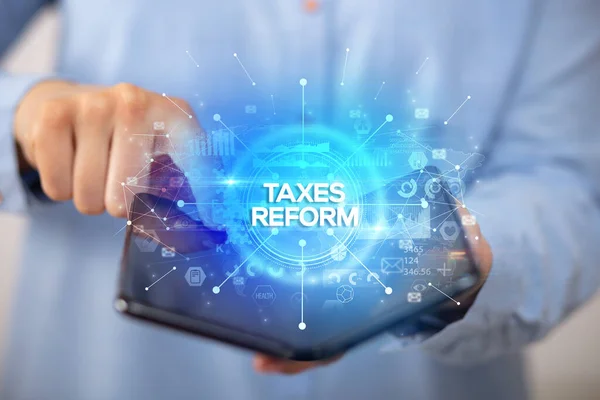 持可折叠智能手机的商人 带着税务改革的题词 新的商业理念 — 图库照片