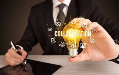 İşadamı elinde İşbirliği yazısıyla ampul tutuyor, sosyal medya kavramı