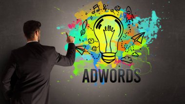 İş adamı desenli beton duvara ADWorDS yazısıyla renkli ampul çiziyor, yeni iş fikri kavramı