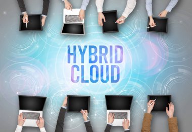 HYBRID CLOUD insciption, web güvenlik kavramı olan bir dizüstü bilgisayarın önünde bir grup insan
