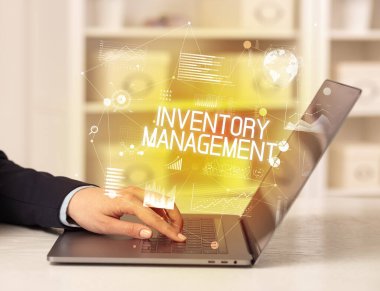 Bilgisayarında INVENTORY MANAGEMENT yazıtları ve modern iş konseptiyle çalışan bir iş adamının yan görüntüsü